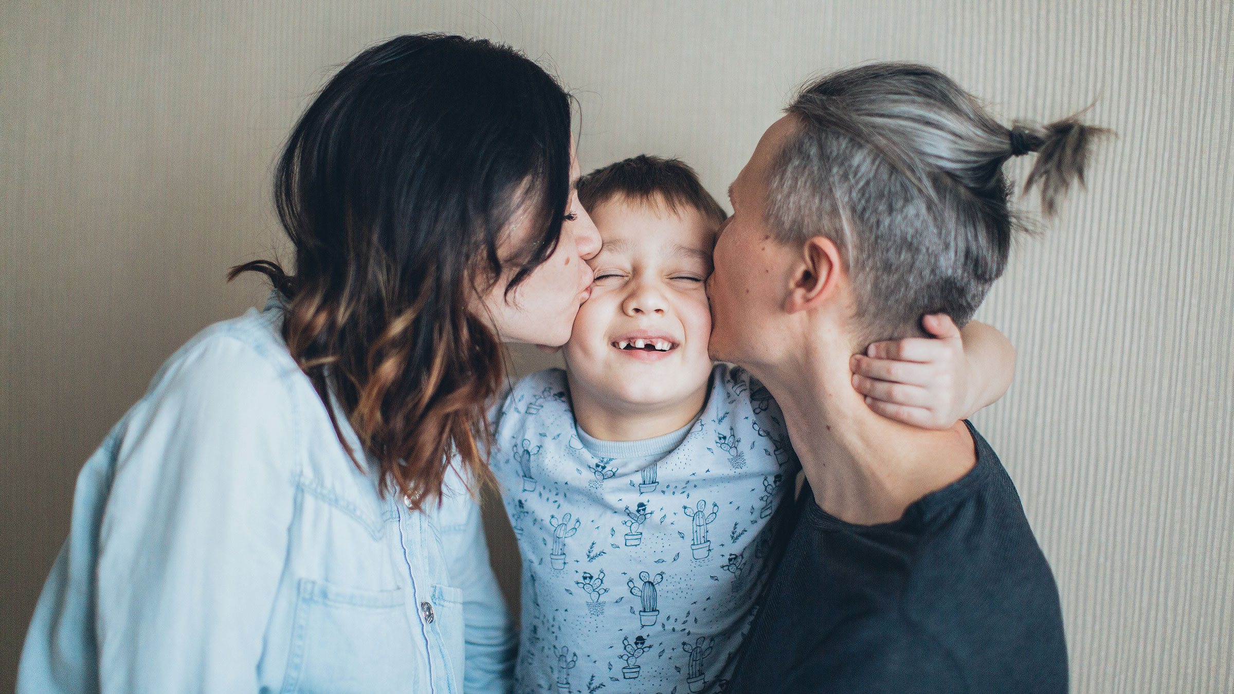 two parents kiss their child