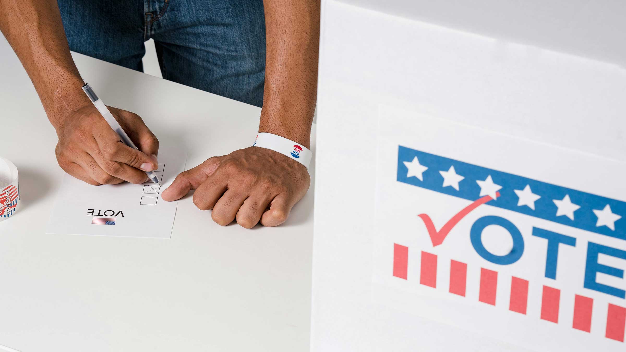 person writing on paper next to "Vote" box