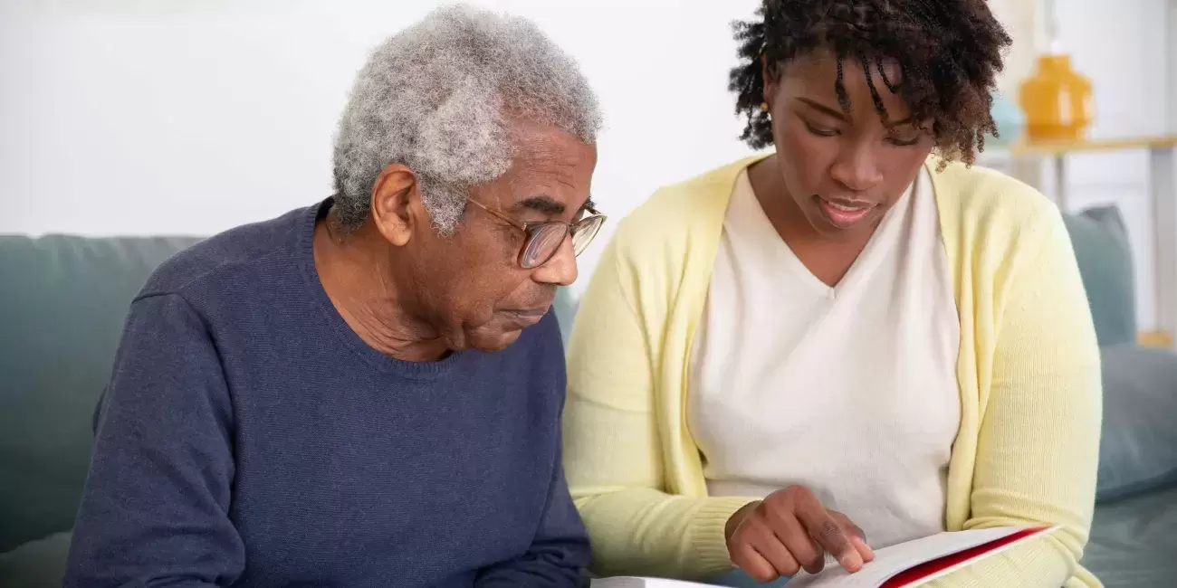 Younger person looks at book with older person