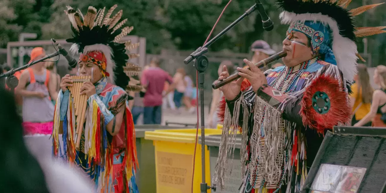 Indigenous people in tribal dress play instruments