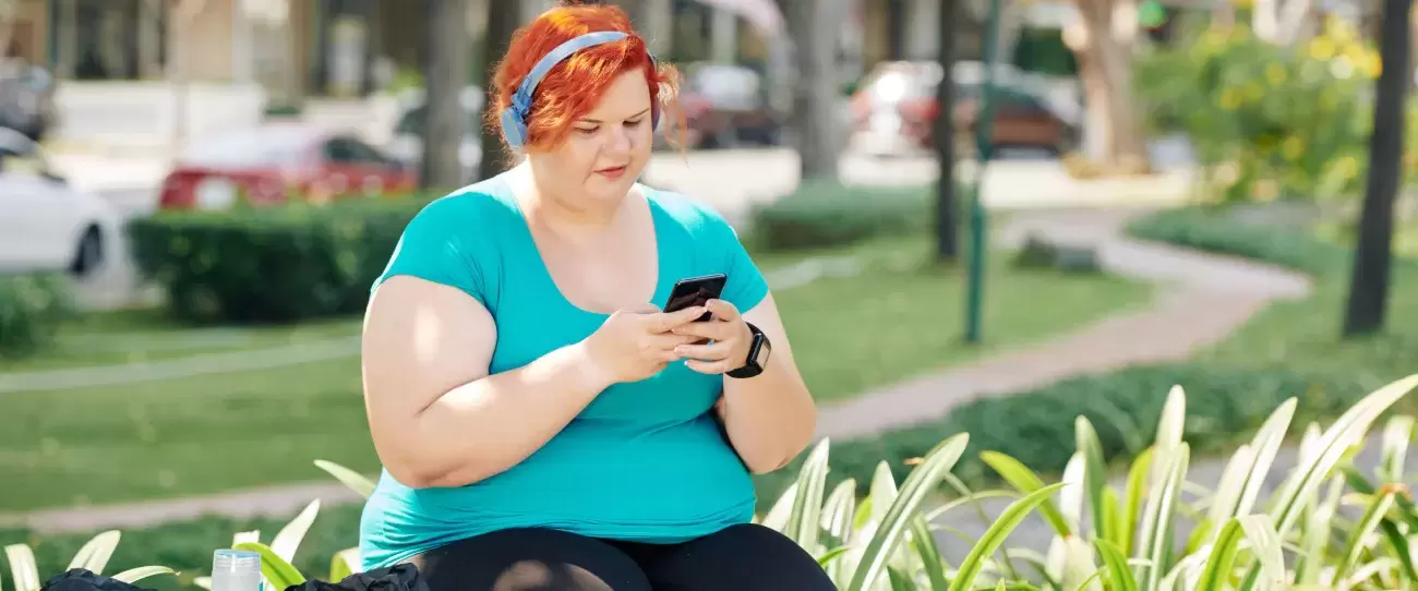 person sits outside and looks at their phone