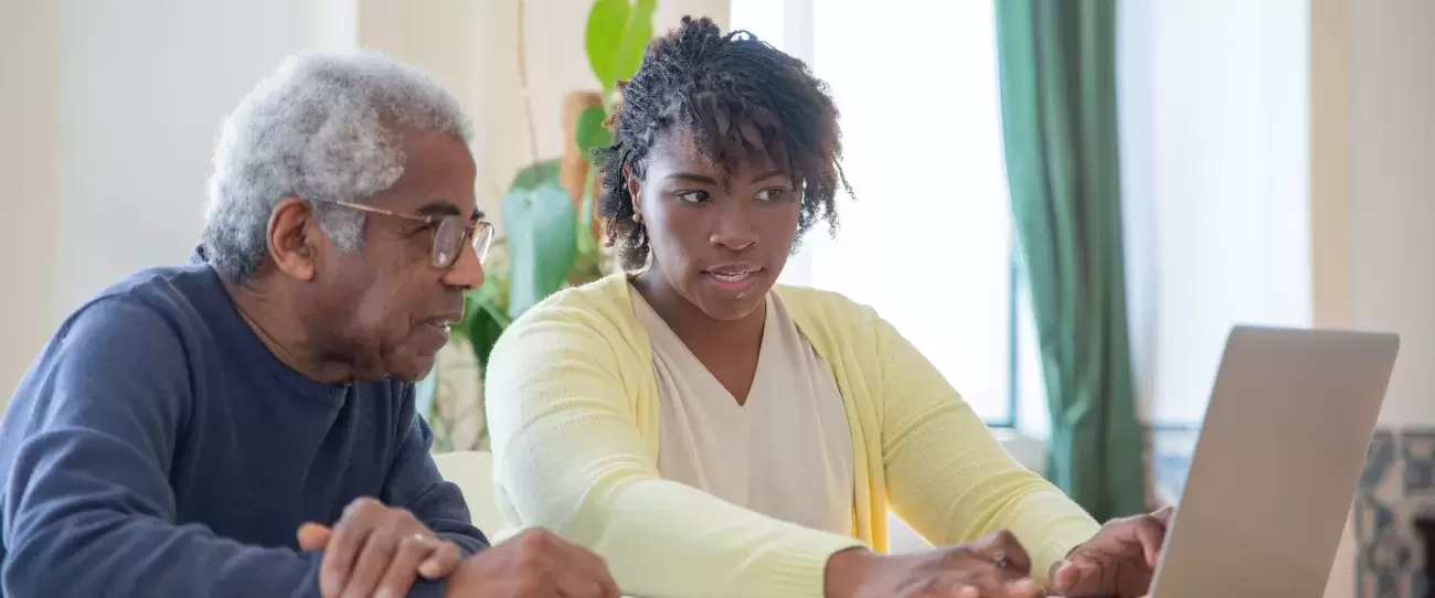 young person helps older person on computer