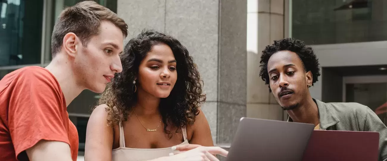 group of people sit at a table looking at computers