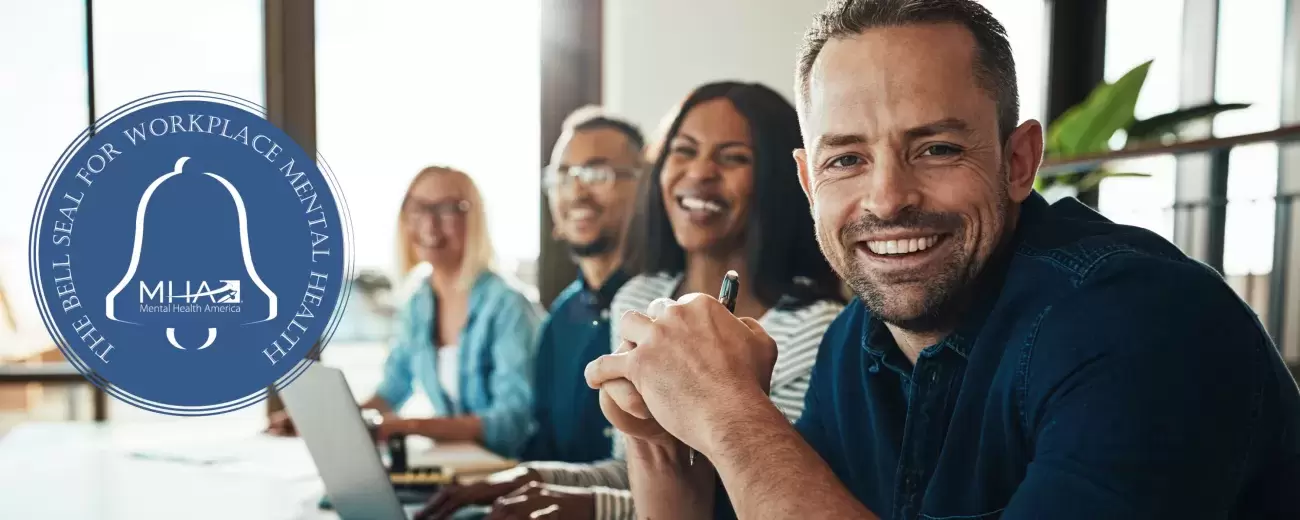 people at office table smile with Bell Seal logo