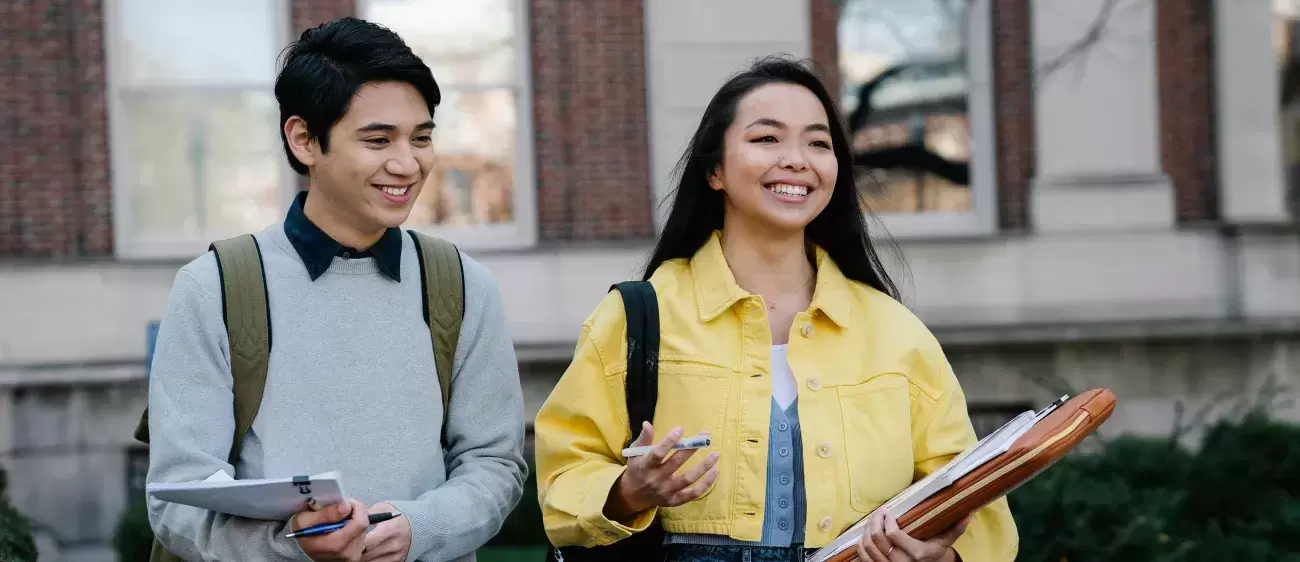 two people wearing backpacks walking and talking 