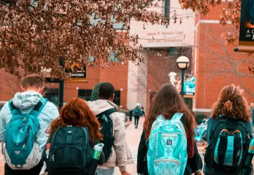 students with backpacks walk on a campus