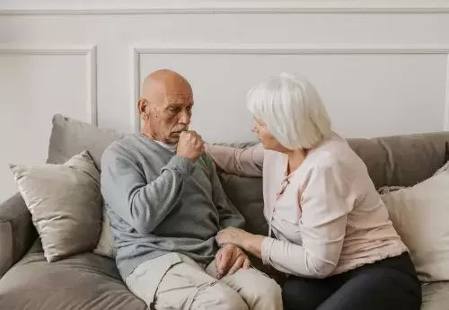 one person comforts another sitting on couch together