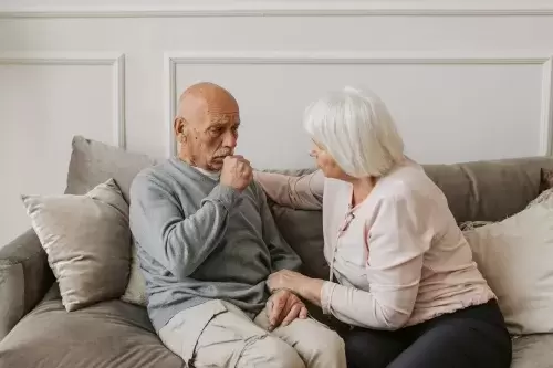 one person comforts another sitting on couch together